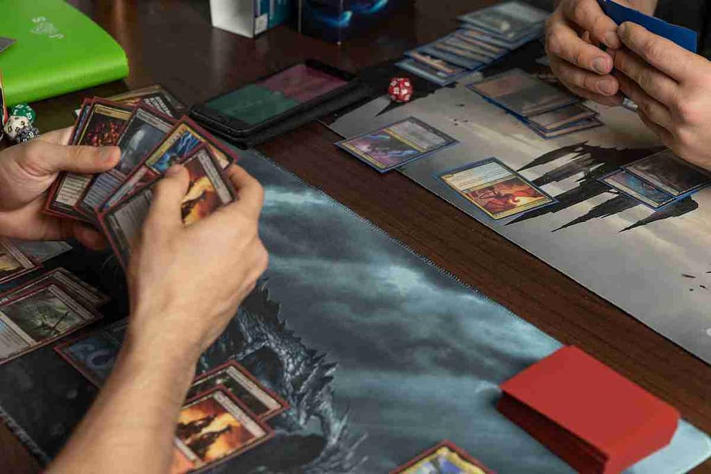2 players across from each other playing magic the gathering on playmats