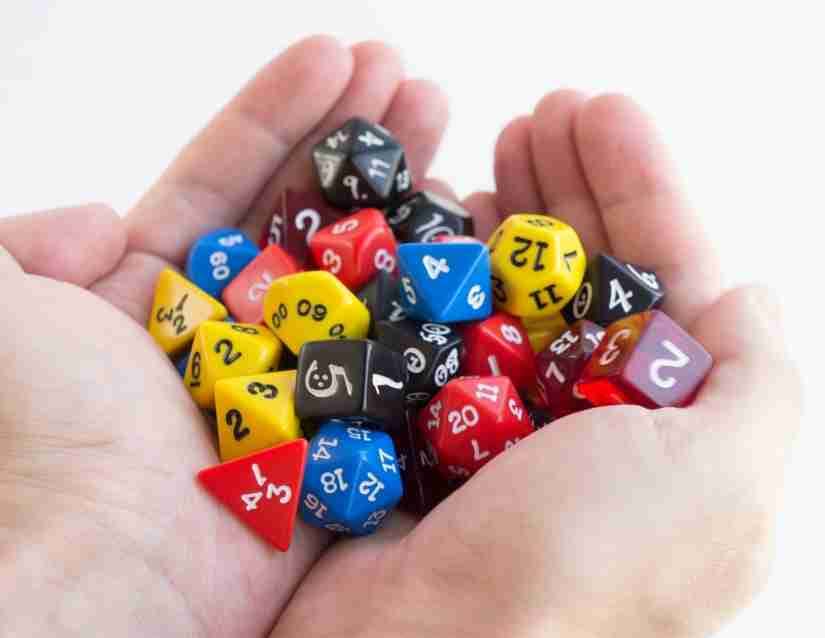 pair of hands holding a couple dozen dice of different side counts